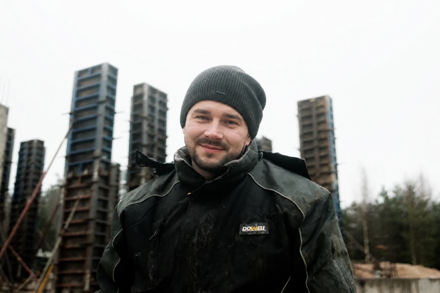 Специалист в рабочей куртке на фоне опор в опалубке после завершения работ